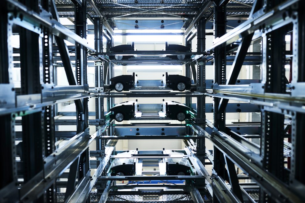 BN Lichtbilder Close-up van meerdere niveaus van een automatisch parkeersysteem, waarop lege metalen platforms en rails te zien zijn die worden gebruikt om voertuigen verticaal te verplaatsen en op te slaan.